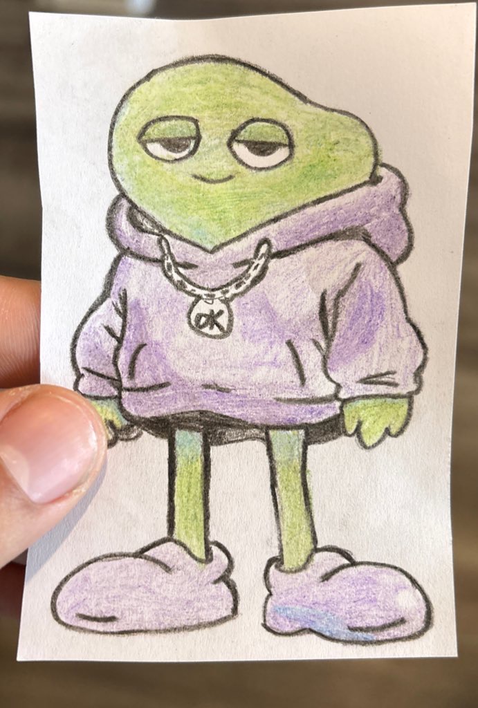 The original hand-drawn Chill Frog sketch, colored pencil on paper, held in hand